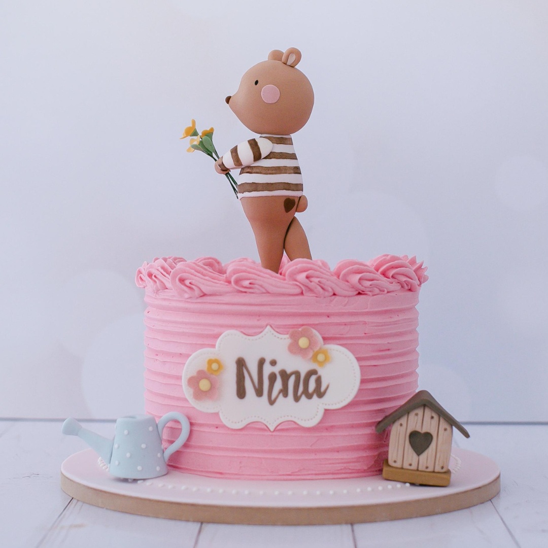 Bolo rosa coberto com buttercream e decorado com ursa Nina em pasta americana